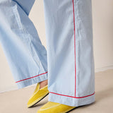 Light blue pants with red piping and yellow shoes on a neutral background
