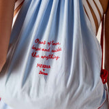 White drawstring bag with red text held by a person