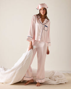 Woman wearing a pink striped pajama set with matching headband on a white background