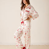 Woman wearing a white pajama set with red accents and lip print on a plain background