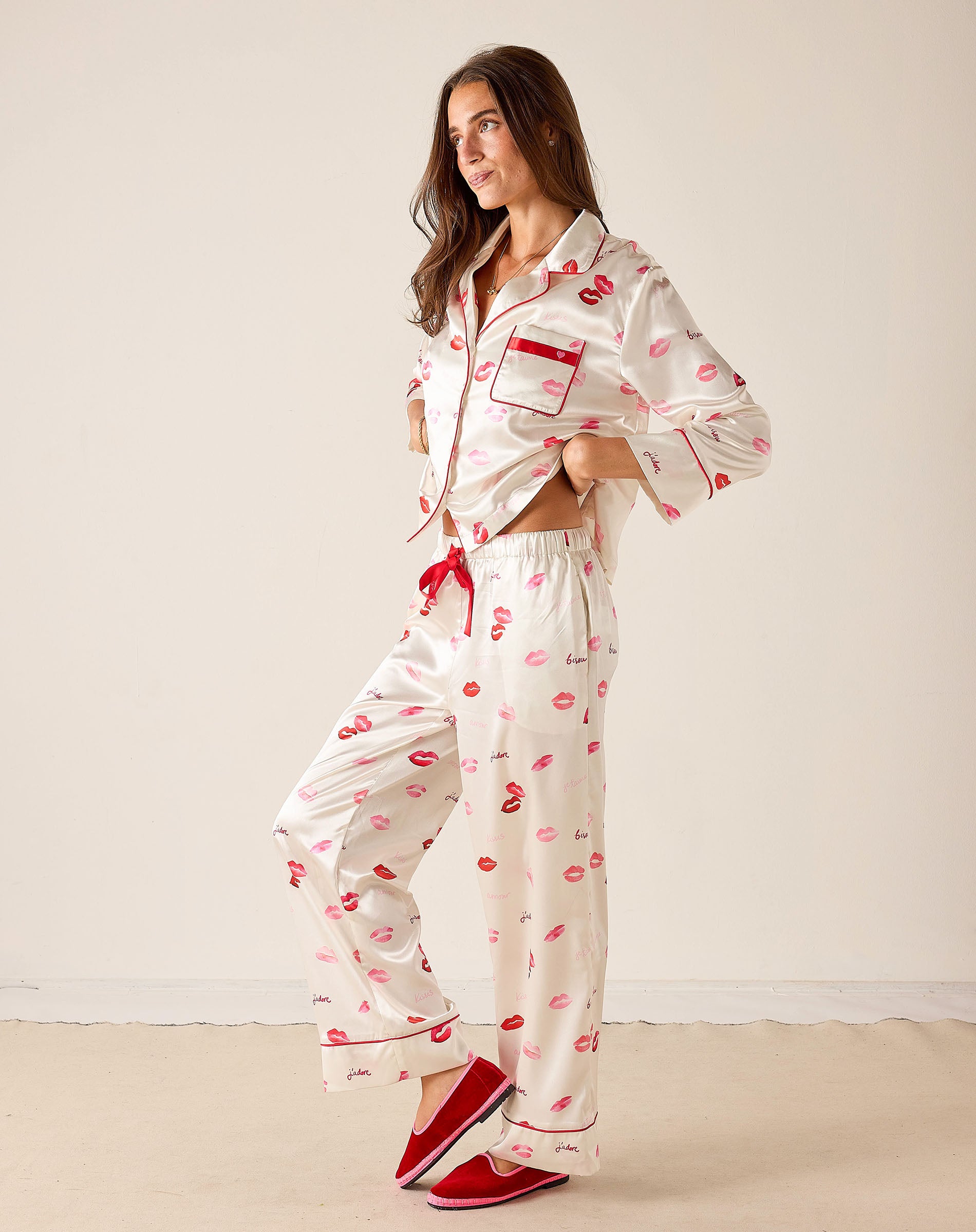 Woman wearing a white pajama set with red accents and lip print on a plain background