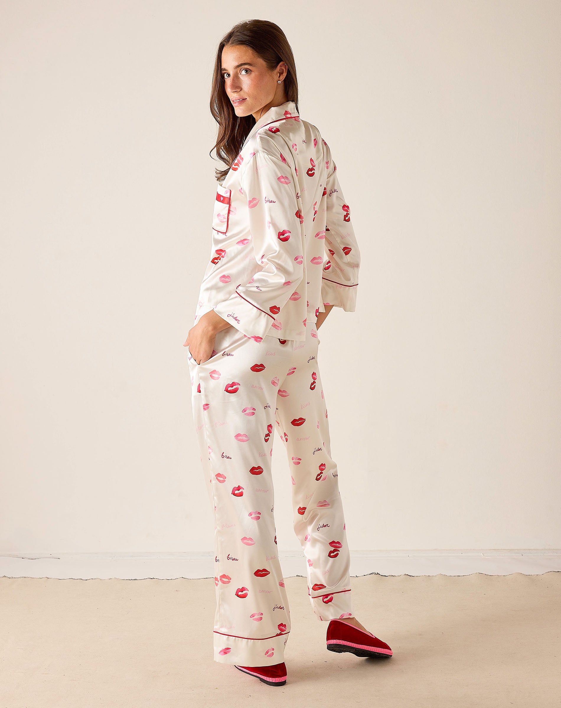 Woman wearing a pajama set with red lip prints on a white background