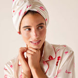Woman wearing a matching headscarf and pajama set with lip print design on a plain background