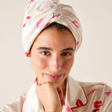 Woman wearing a matching headscarf and robe with red lip prints and 'Lise Charmel' branding.