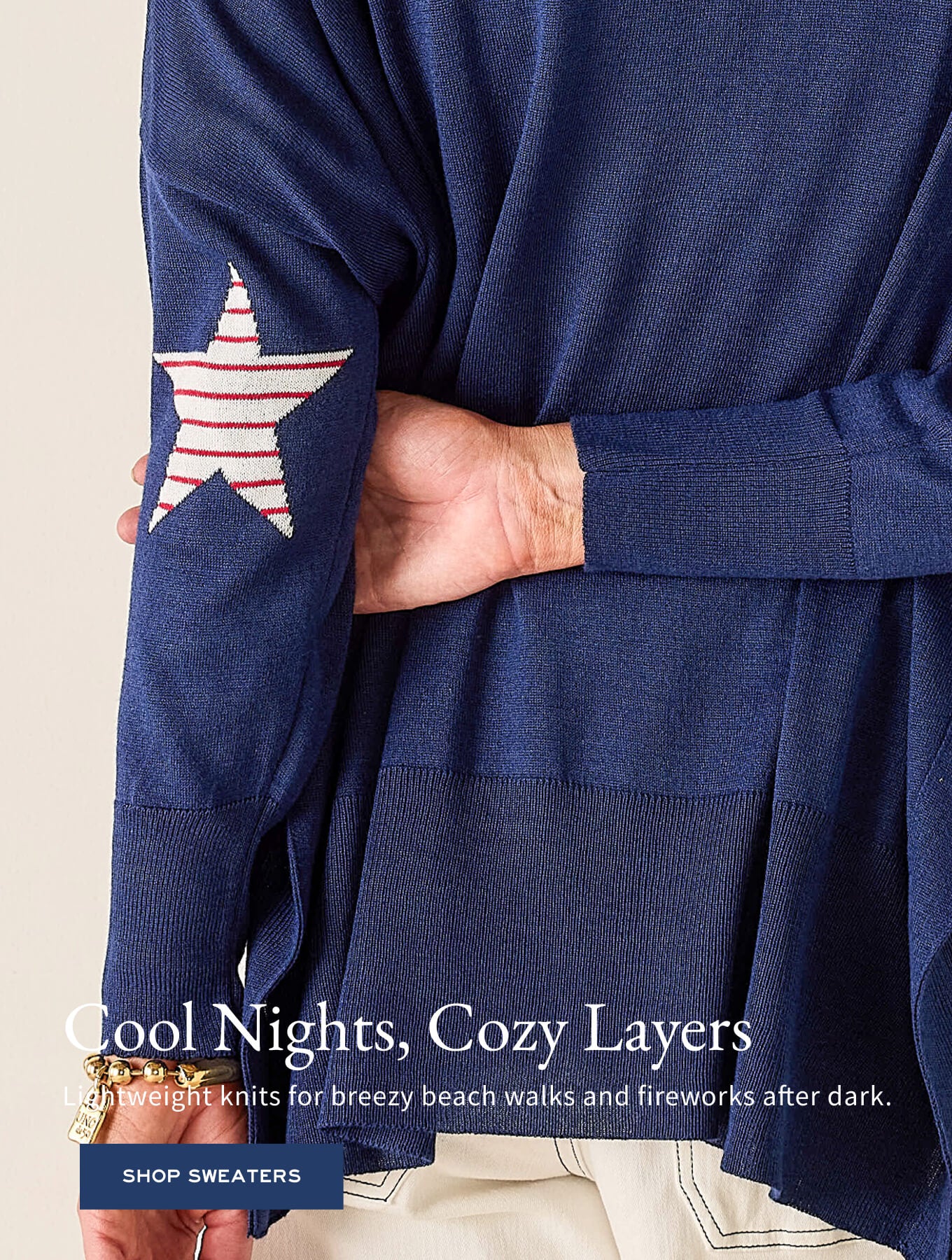 Model wearing a navy blue knit sweater with a white star and red stripe detail on the sleeve.