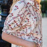 Woman wearing a sweet clementine flower market print blouse with short sleeves and floral details.