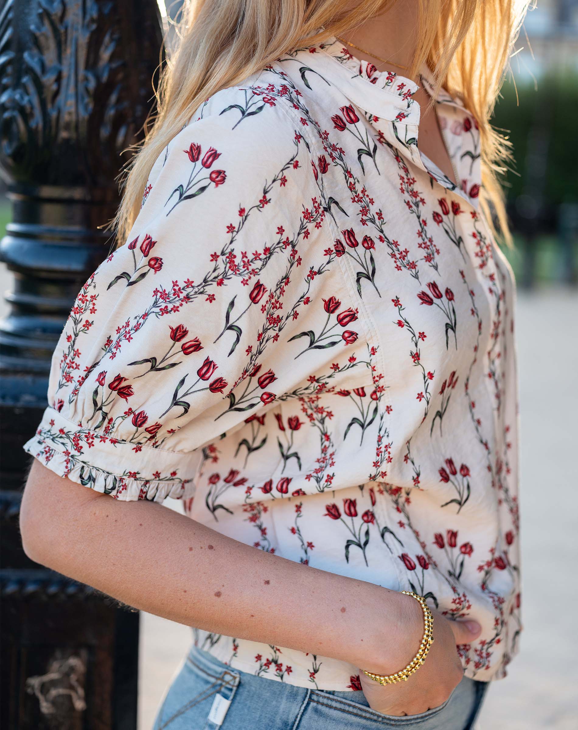 Woman wearing a sweet clementine flower market print blouse with short sleeves and floral details.