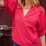 Person wearing a red textured blouse with a blurred background