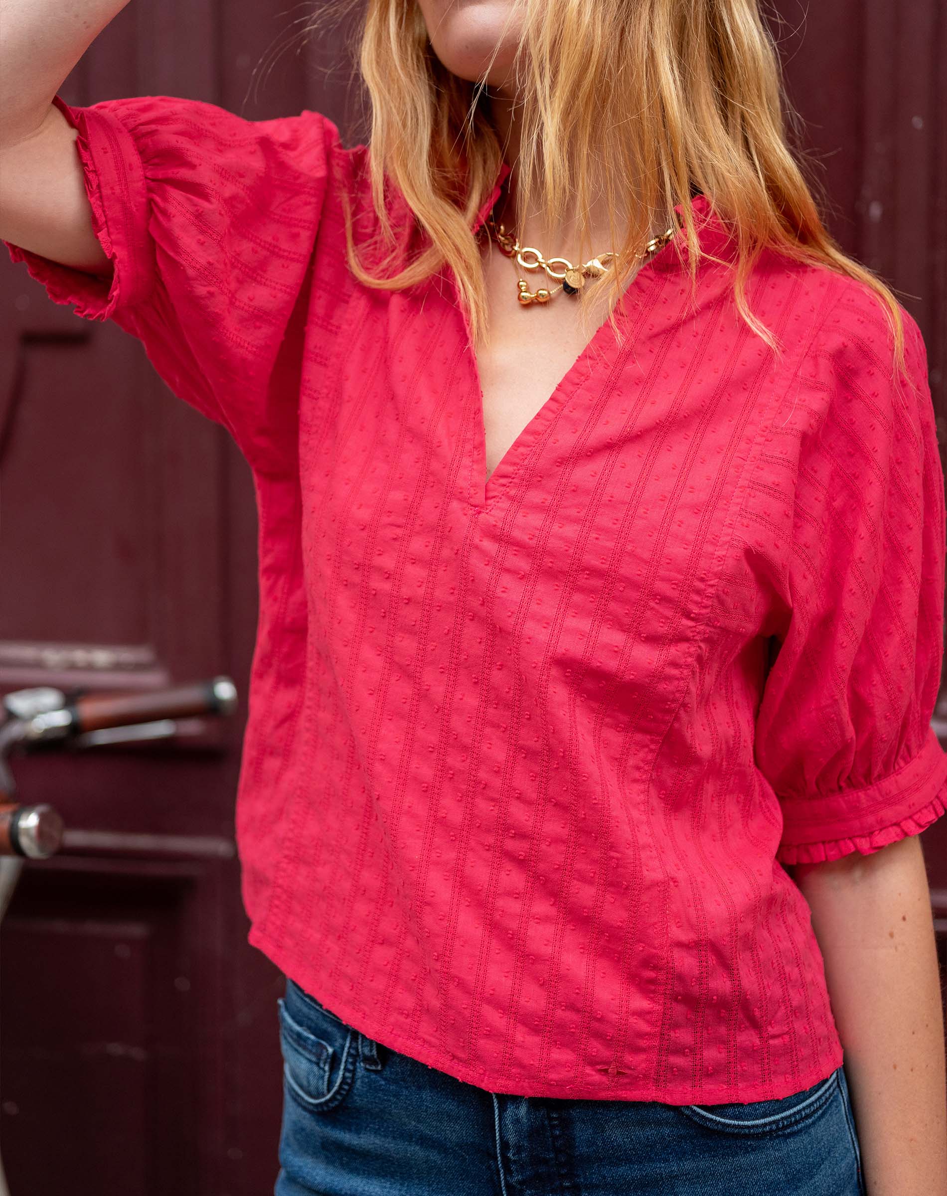 Person wearing a red textured blouse with a blurred background