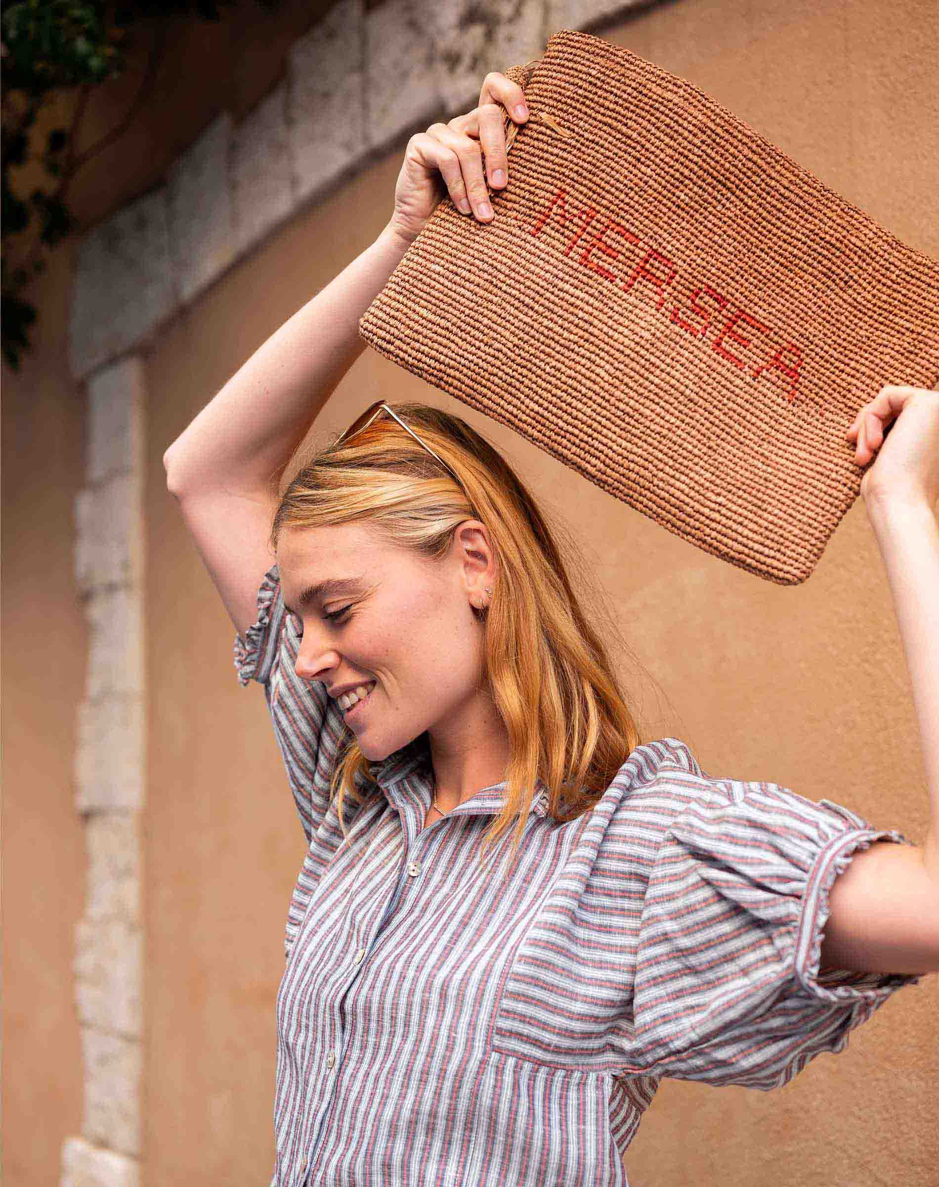 Woman holding a doormat with 'NEREA' branding outdoors.