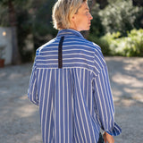 MERSEA ladies' travel-ready back view of women's travel-friendly blue and white striped button-down shirt with a brown decorative tab on the back yoke.