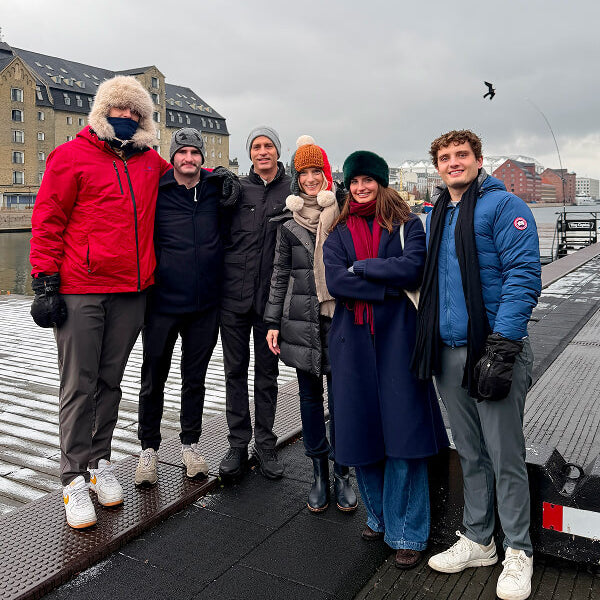 Group of people posing together on a dock with a cityscape in the background