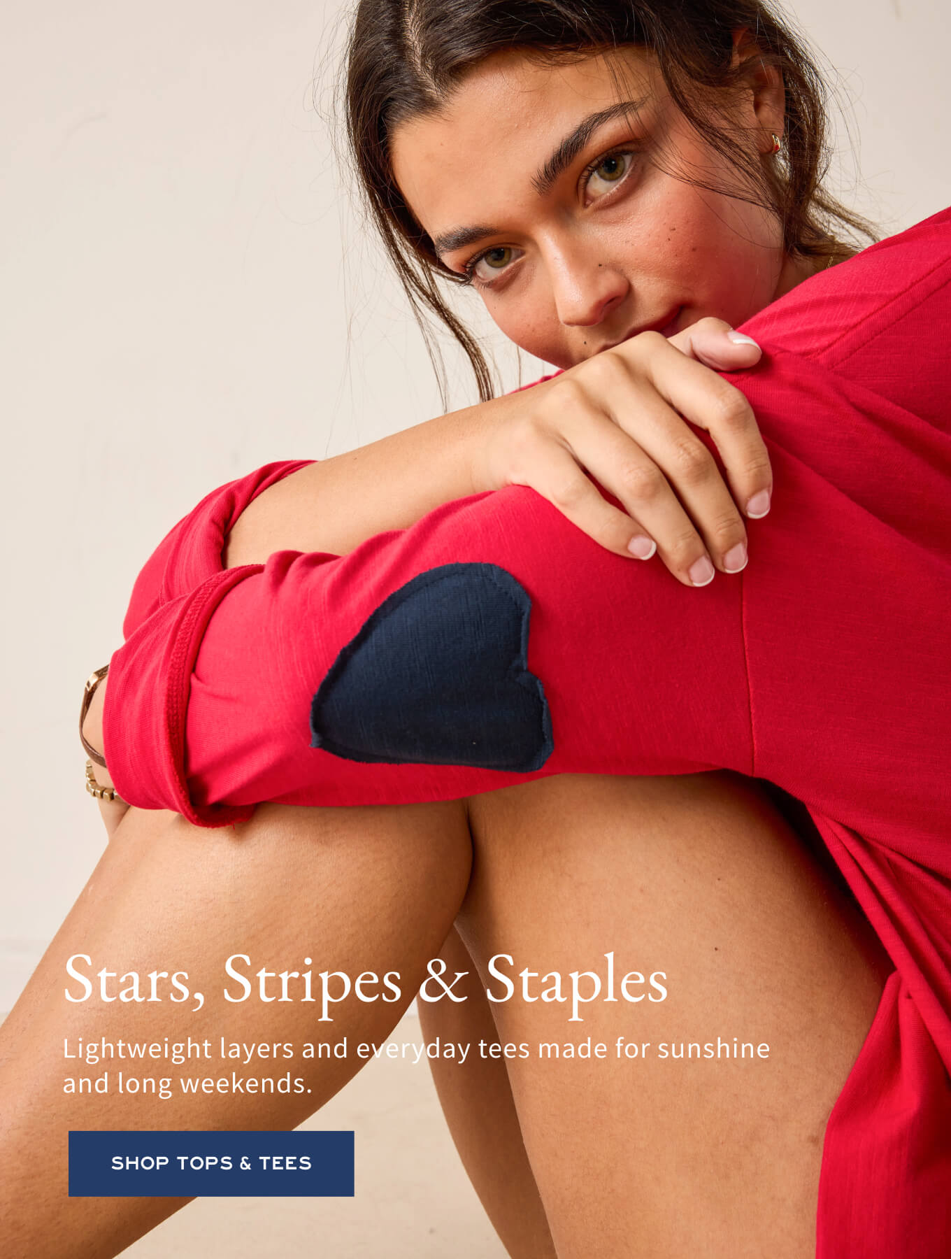 Model in a red long-sleeve tee with a heart patch on the sleeve, posed against a soft background.