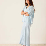Woman wearing a light blue outfit with white sneakers on a beige background