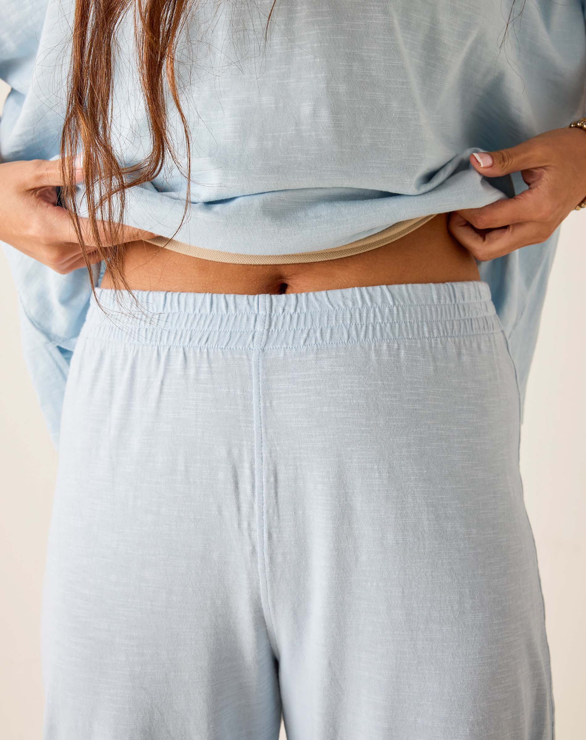 Person wearing light blue pajama set with a neutral background