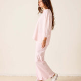 Person wearing a pink outfit with white sneakers on a plain background