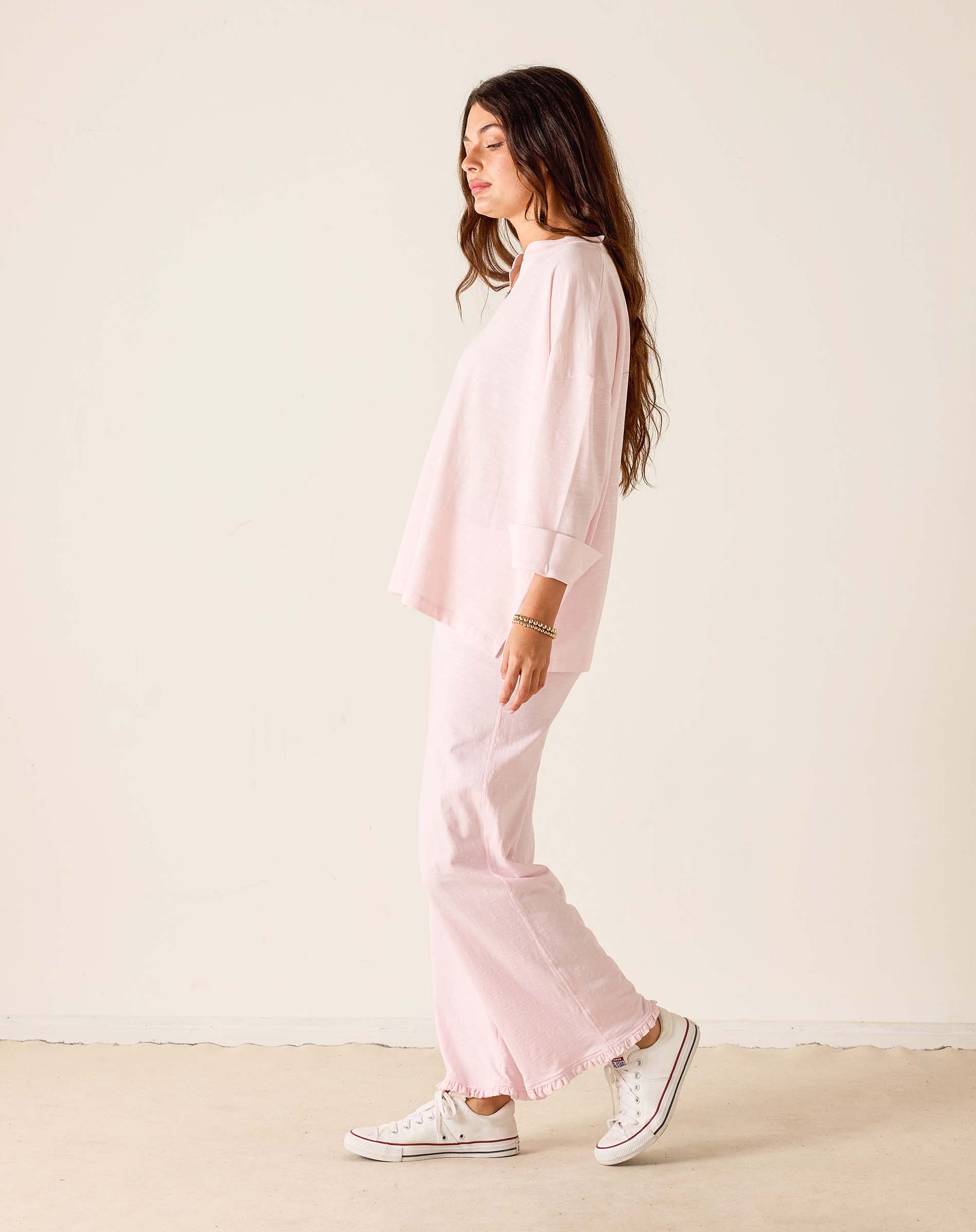 Person wearing a pink outfit with white sneakers on a plain background
