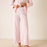 Person wearing a pink outfit with wide-leg pants against a plain background