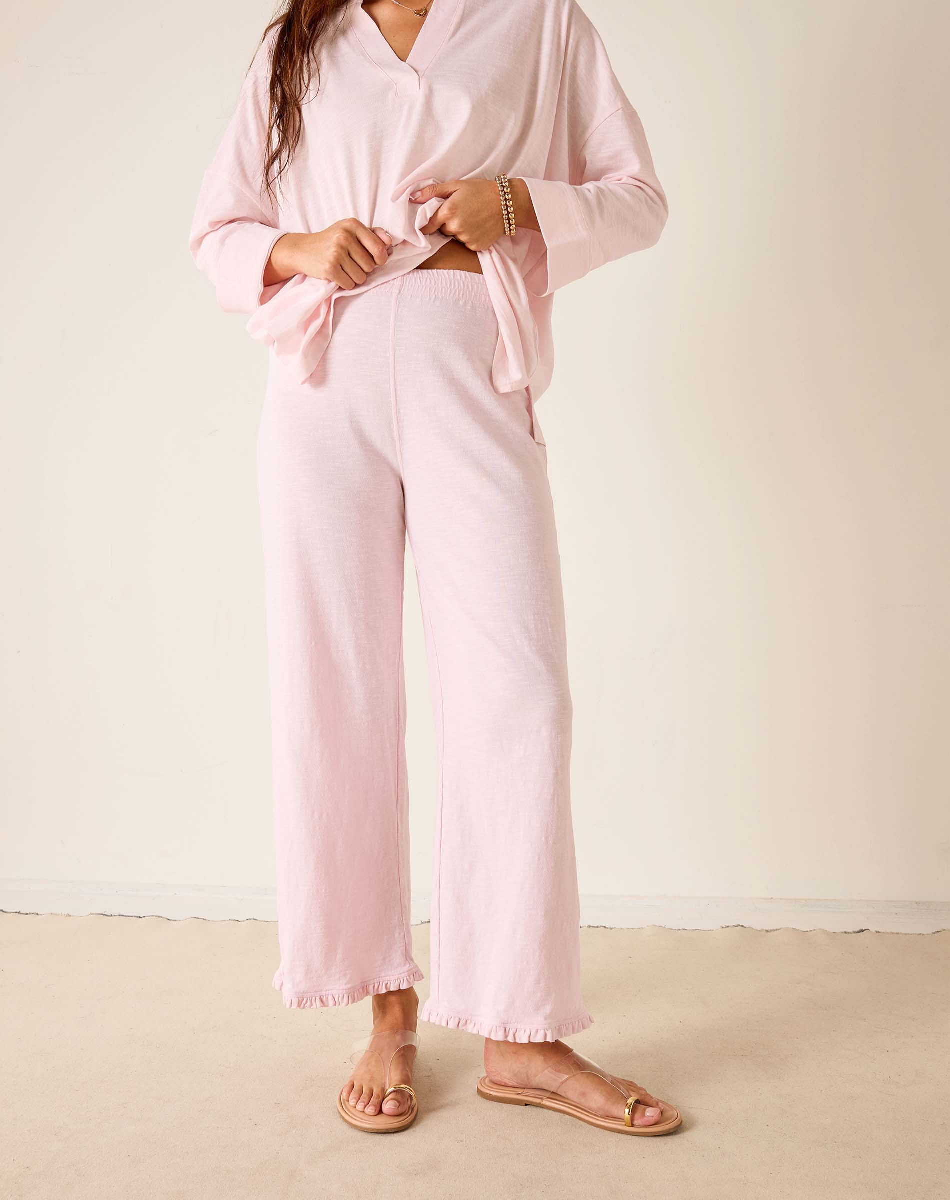 Person wearing a pink outfit with wide-leg pants against a plain background