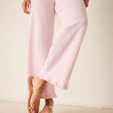 Person wearing light pink pants and sandals on a plain background