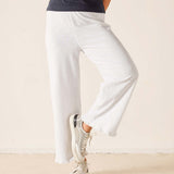 Person wearing white pants and white sneakers on a plain background