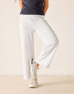 Person wearing white pants and white sneakers on a plain background