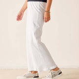 Person wearing white pants and sneakers on a plain background
