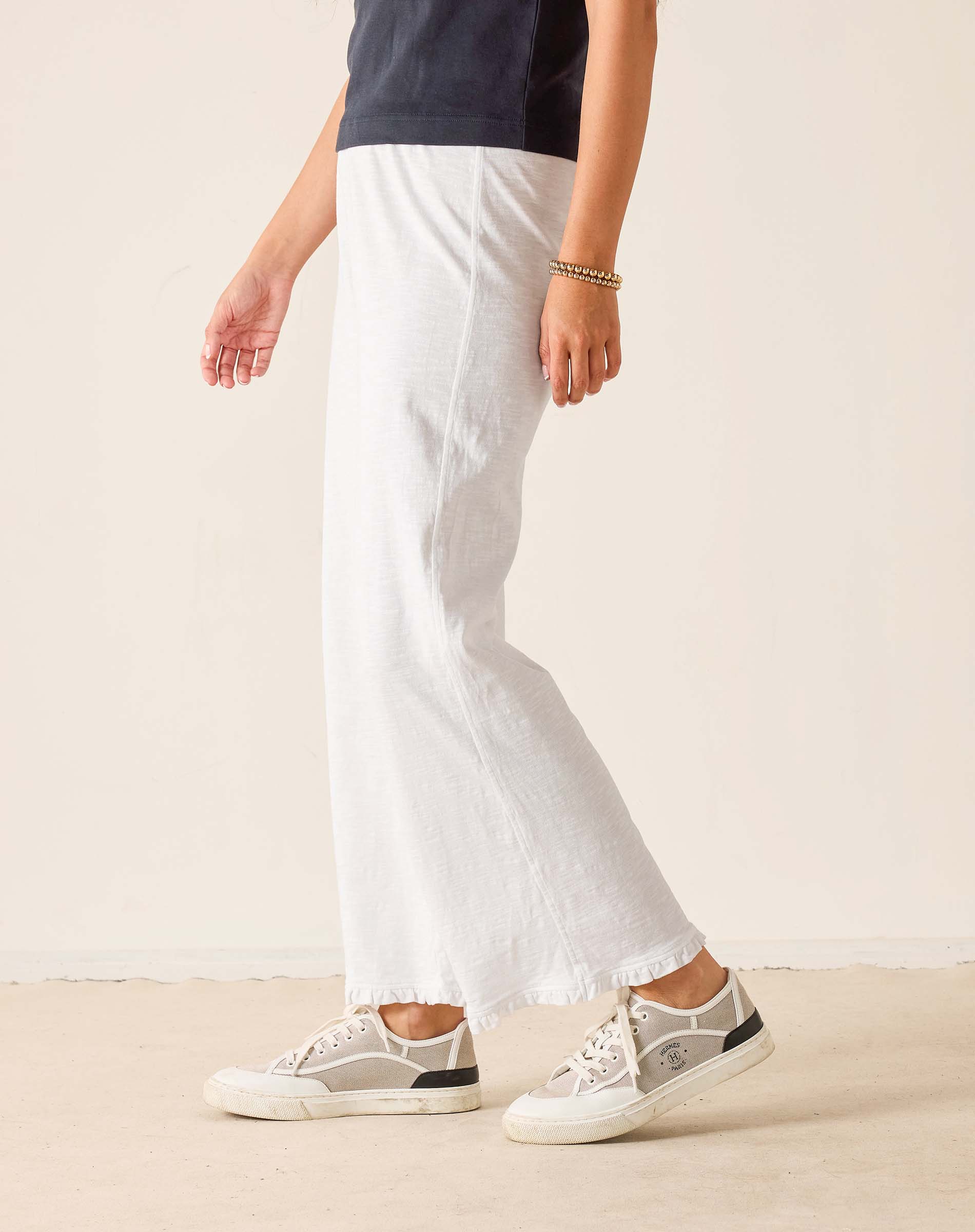 Person wearing white pants and sneakers on a plain background