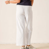 Person wearing white pants and a dark shirt on a plain background