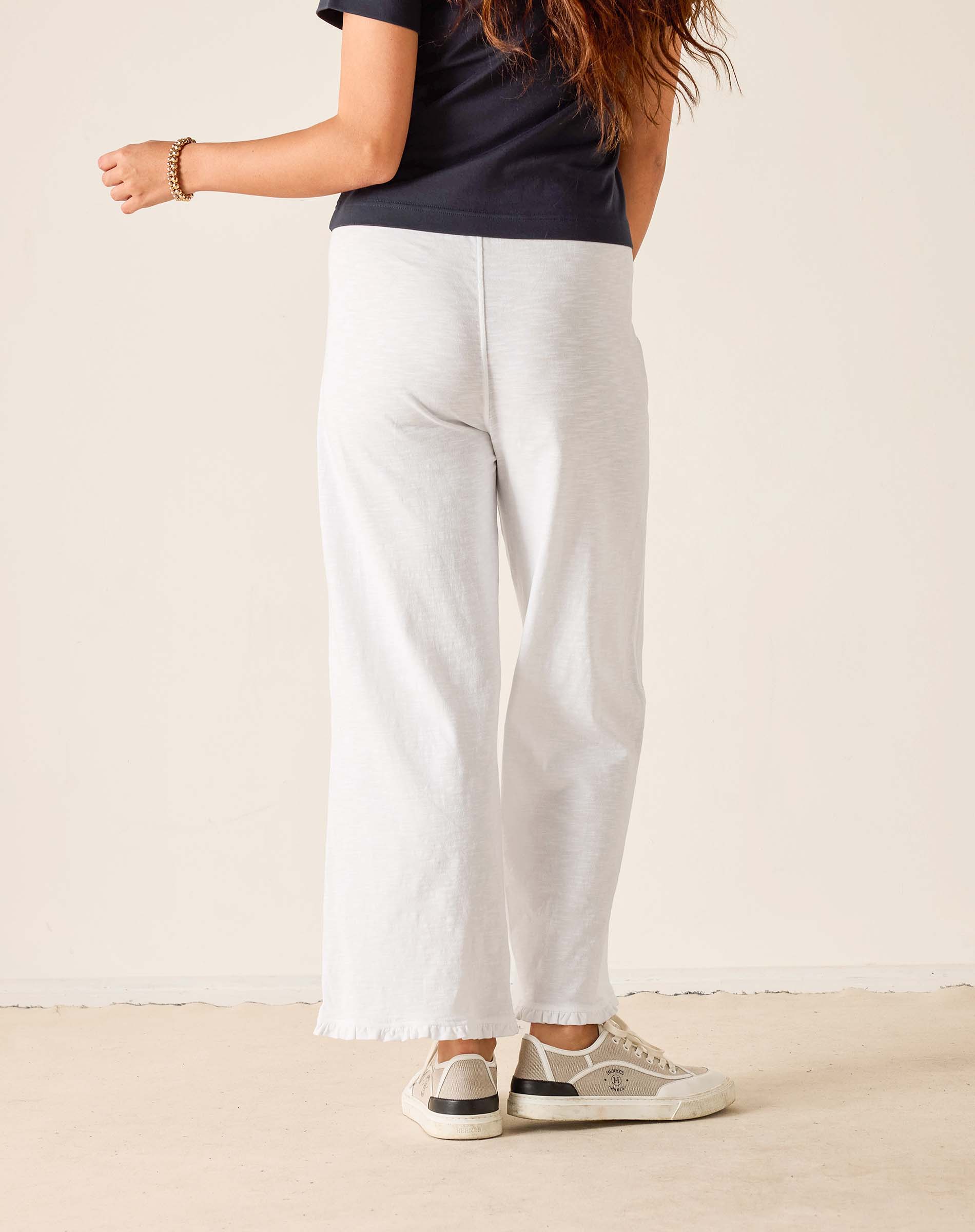 Person wearing white pants and a dark shirt on a plain background