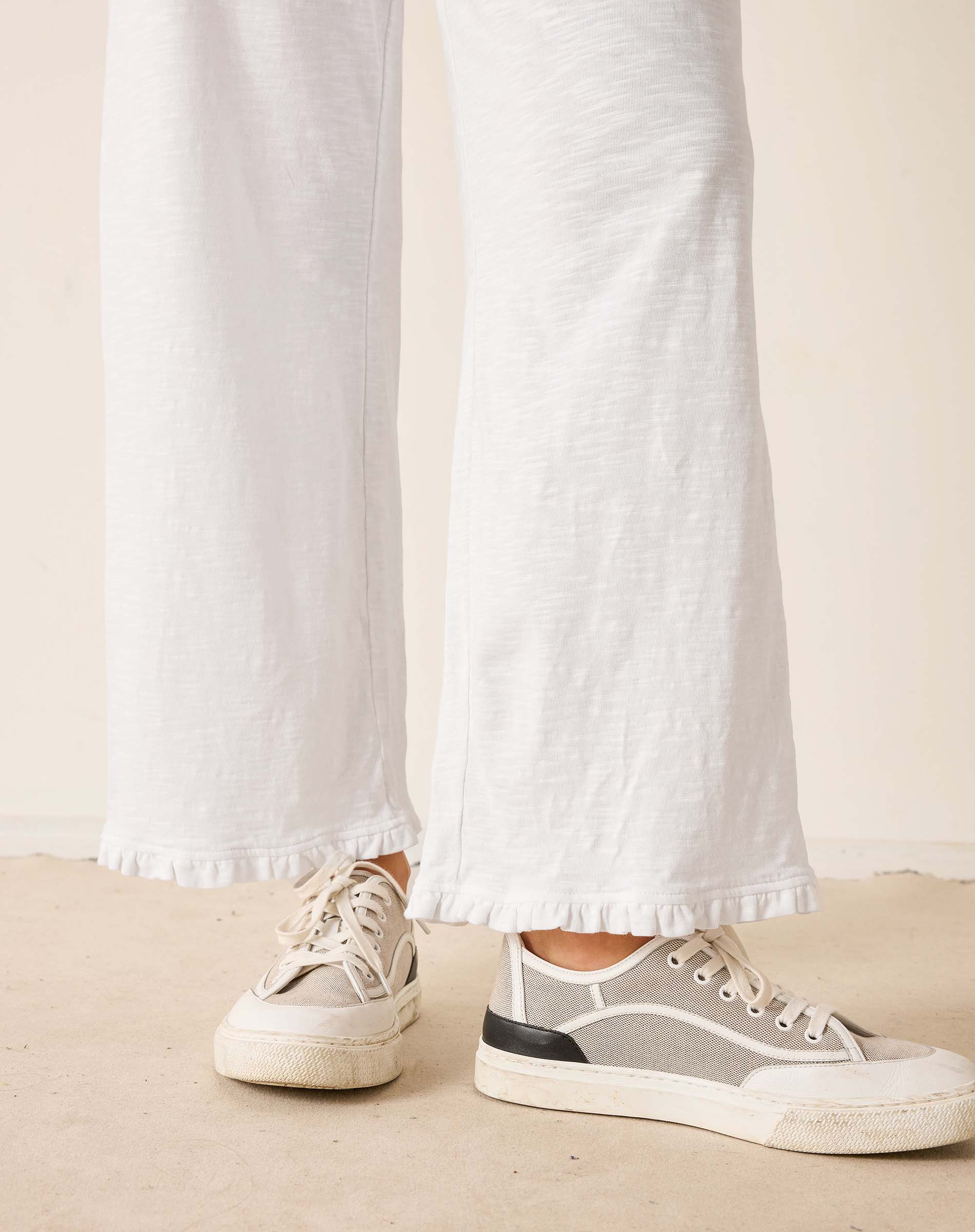 Person wearing white sneakers with a neutral background