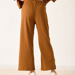 Person wearing brown pants and a matching top on a white background