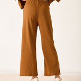 Person wearing brown pants and a matching top on a white background