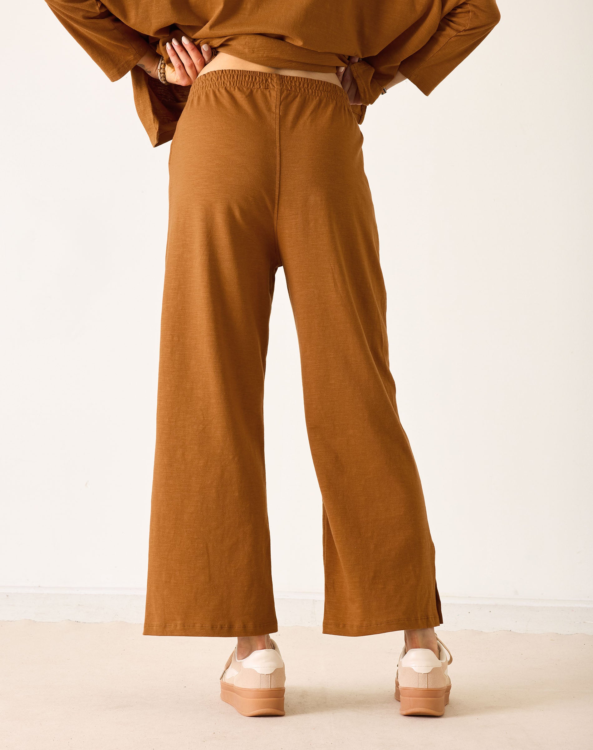 Person wearing brown pants and a matching top on a white background