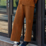 Person wearing a brown outfit standing on a step outside a building.