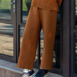 Person wearing a brown outfit standing on a step outside a building.