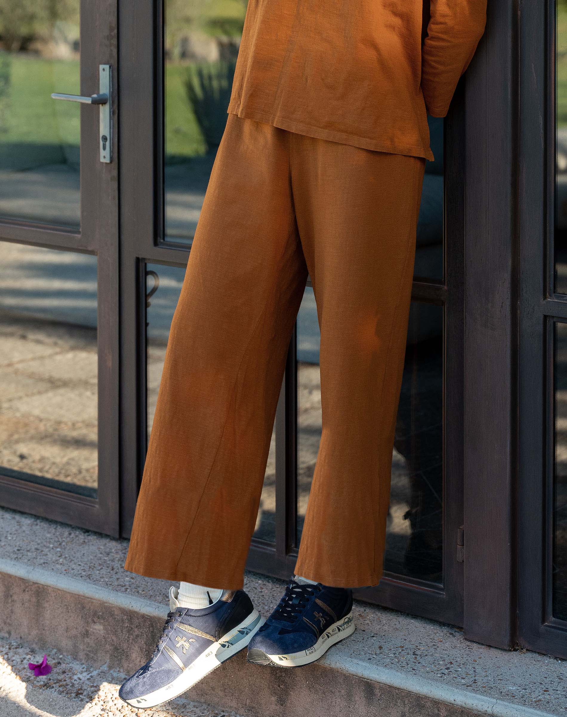 Person wearing a brown outfit standing on a step outside a building.