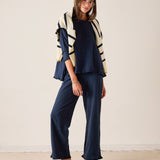 Woman wearing a navy outfit with a striped cardigan against a plain background