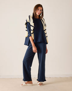 Woman wearing a navy outfit with a striped cardigan against a plain background