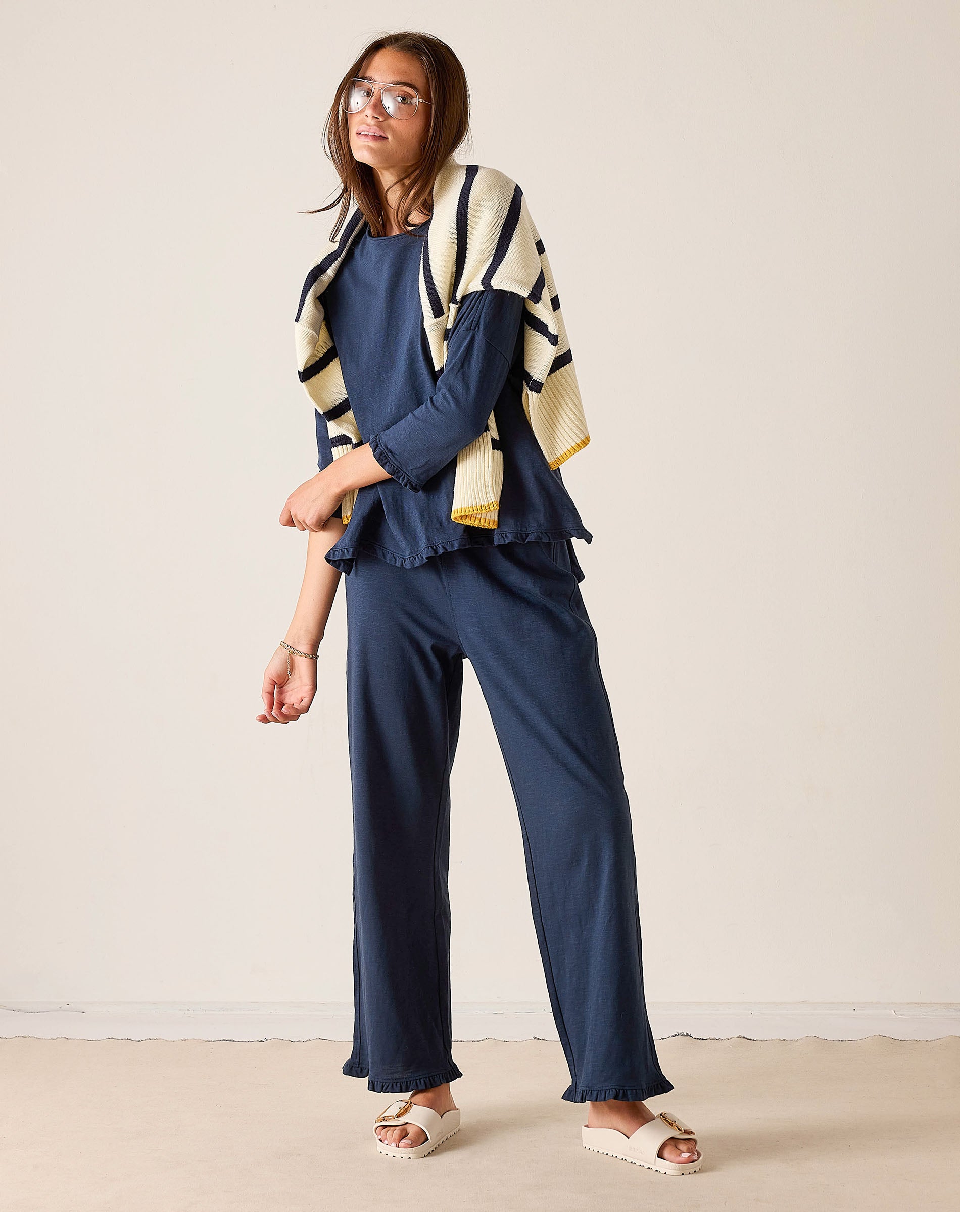 Woman wearing a blue outfit with a striped cardigan against a plain background