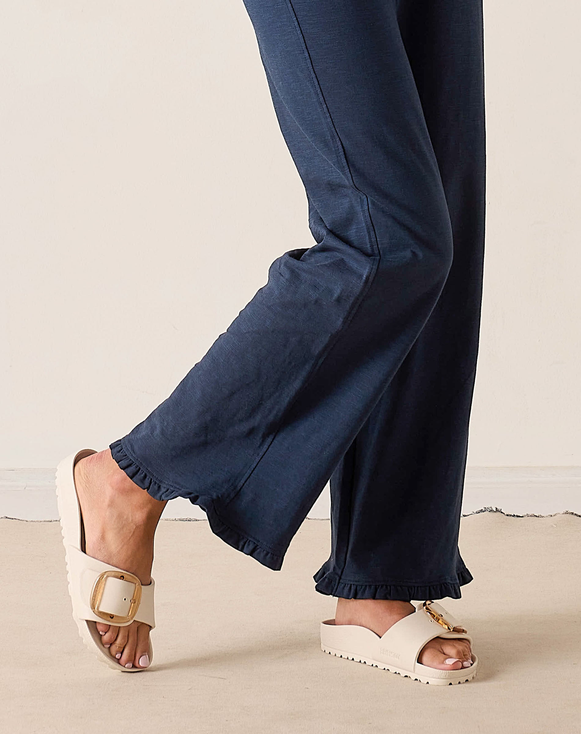 Navy pants worn by a person on a light background
