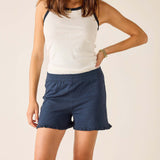 Woman wearing a white tank top and blue shorts on a beige background