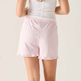 Person wearing a white tank top and pink shorts on a plain background
