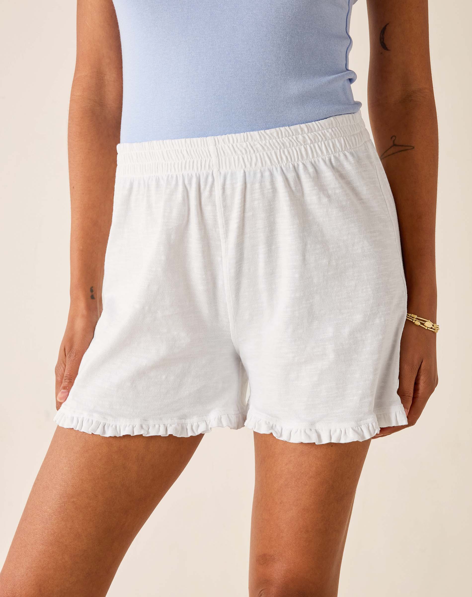 White shorts worn by a person on a beige background