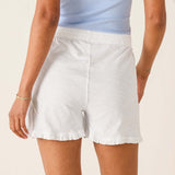 Person wearing white shorts and a light blue top on a beige background