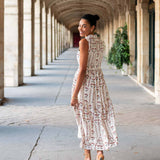 Woman in a floral dress walking through an architectural corridor.