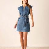 Woman wearing a denim dress with a belt against a plain background