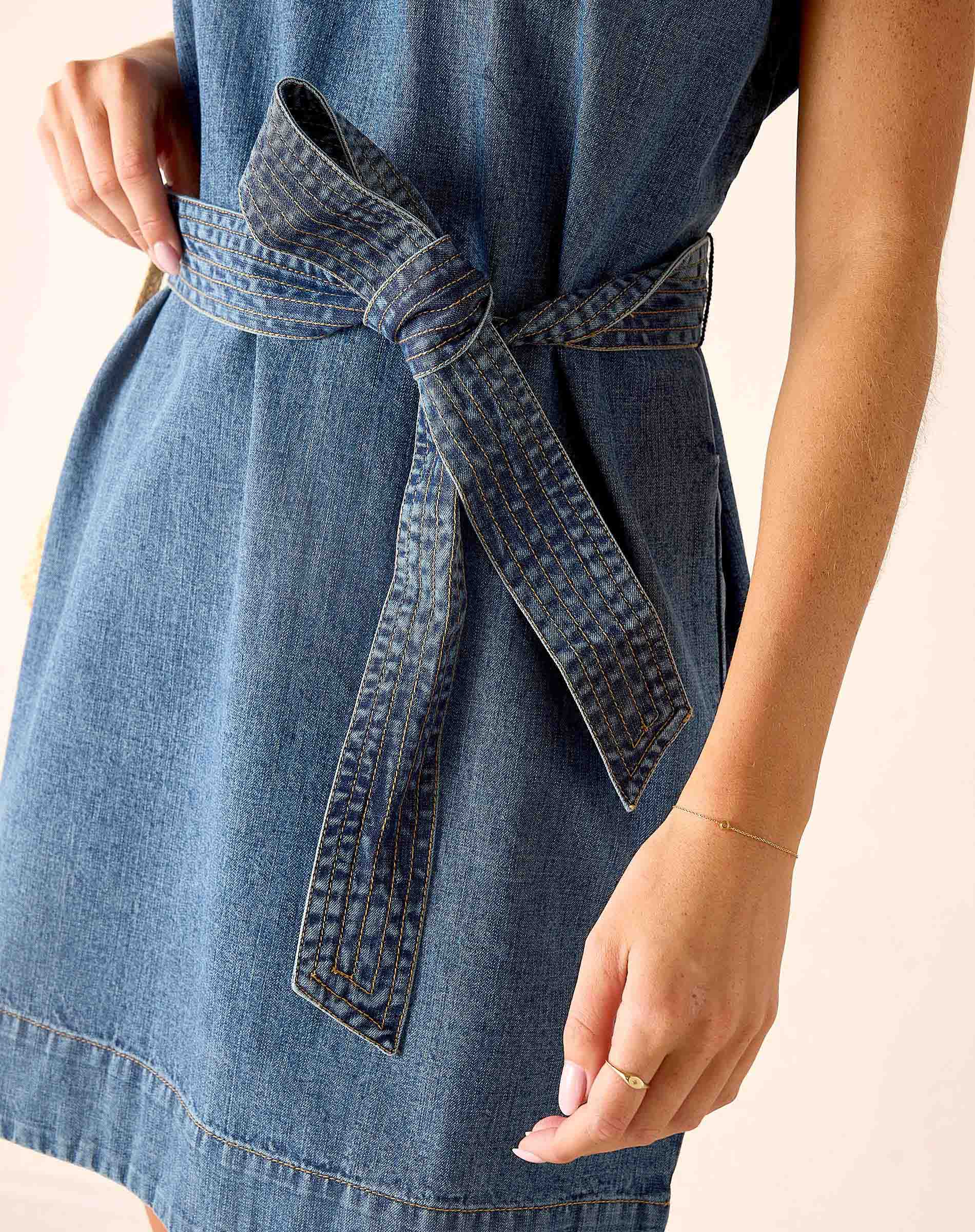Denim dress with a belt on a plain background