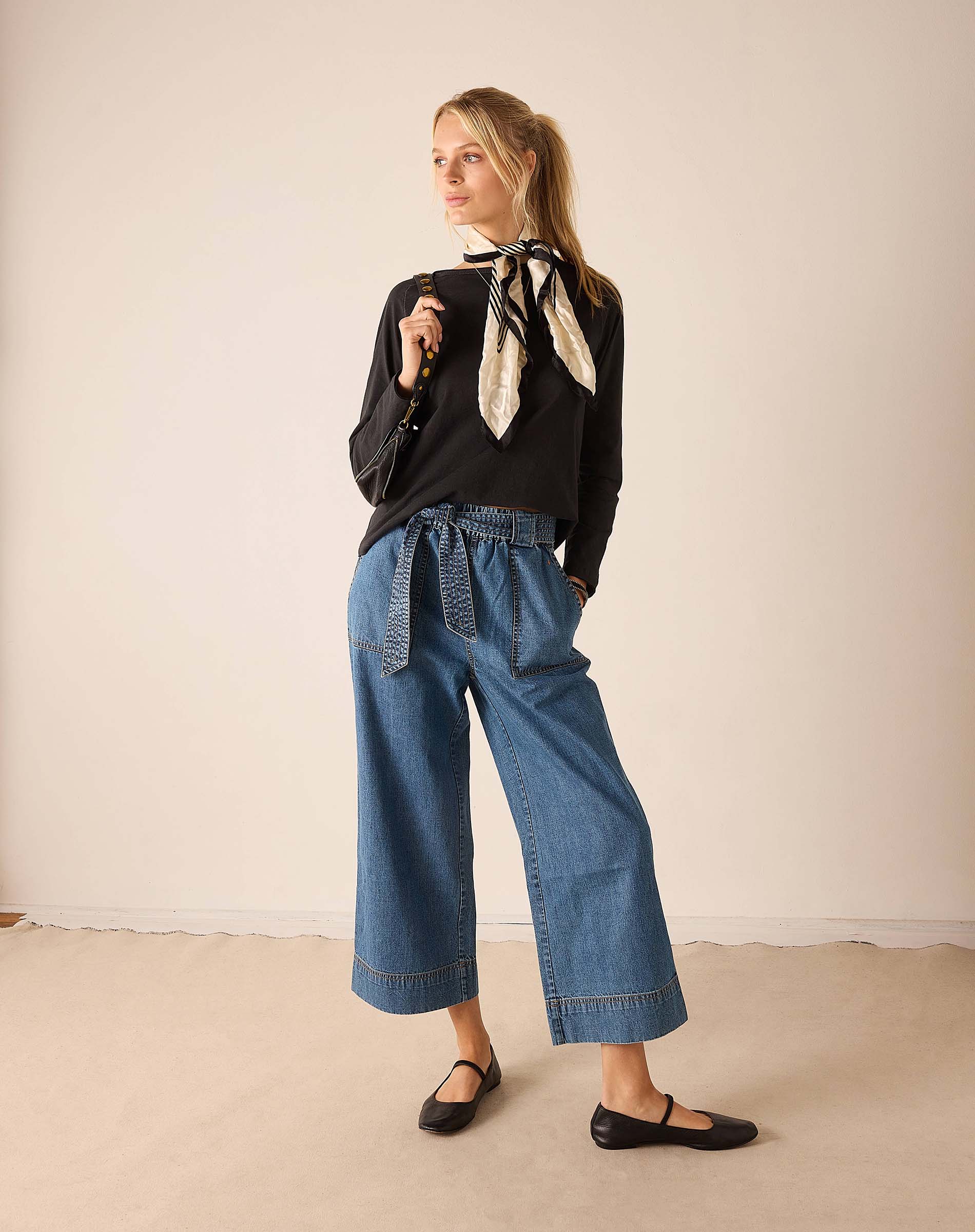 Women's travel-friendly graphite grey raglan tee with a graphic print and wide-leg denim trousers.