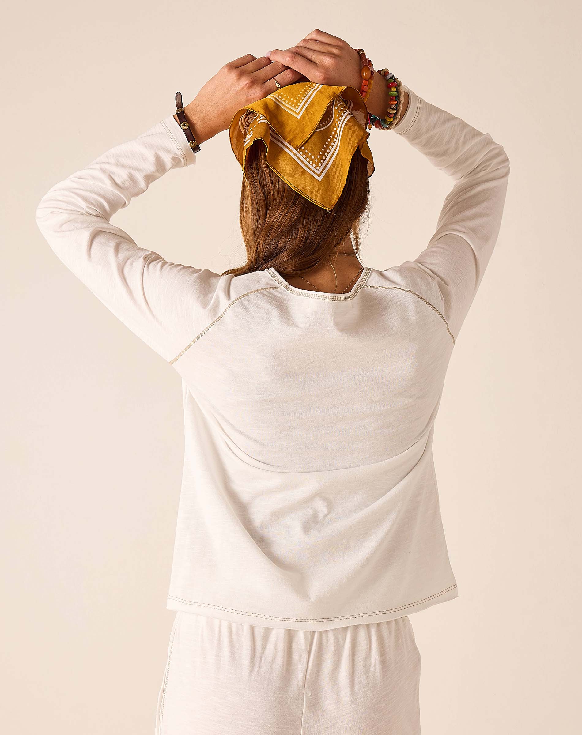Back view of woman wearing a white raglan tee with soft cotton blend fabric.